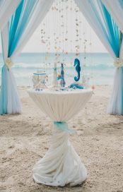 Blue and white wedding aisle in a beach surrounded by palms with the sea on the background